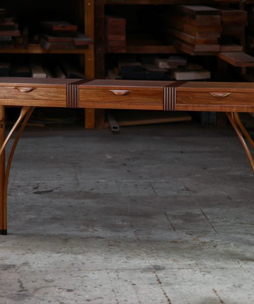 A beautifully composed hall table standing in front of a timber rack in a workshop.