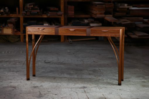 A beautifully composed hall table standing in front of a timber rack in a workshop.