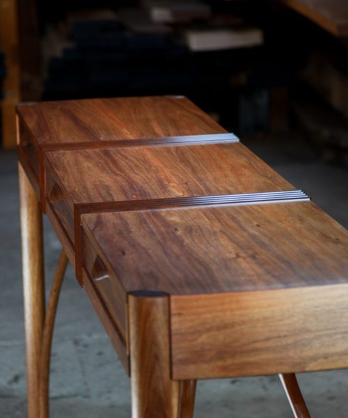 A beautifully composed hall table standing in front of a timber rack in a workshop.