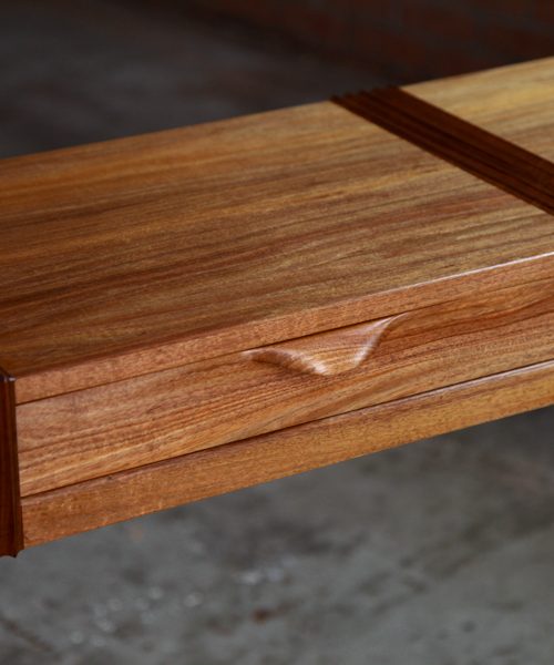 A beautifully composed hall table standing in front of a timber rack in a workshop.