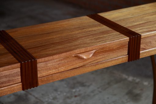 A beautifully composed hall table standing in front of a timber rack in a workshop.