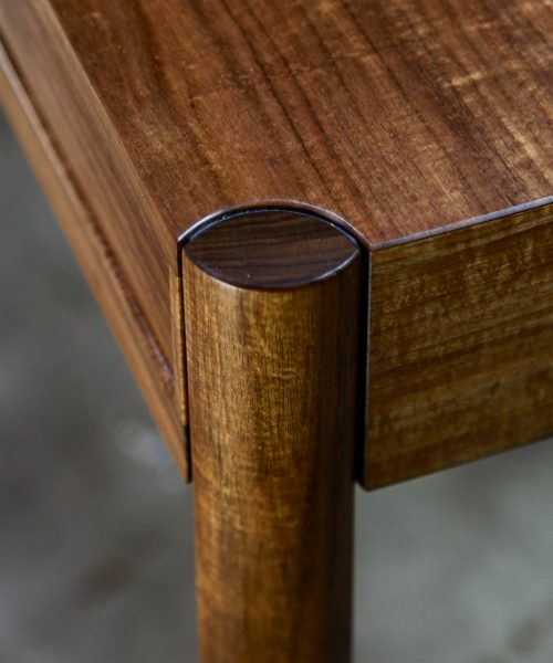A beautifully composed hall table with figured blackwood standing in front of a timber rack in a woodworking workshop.
