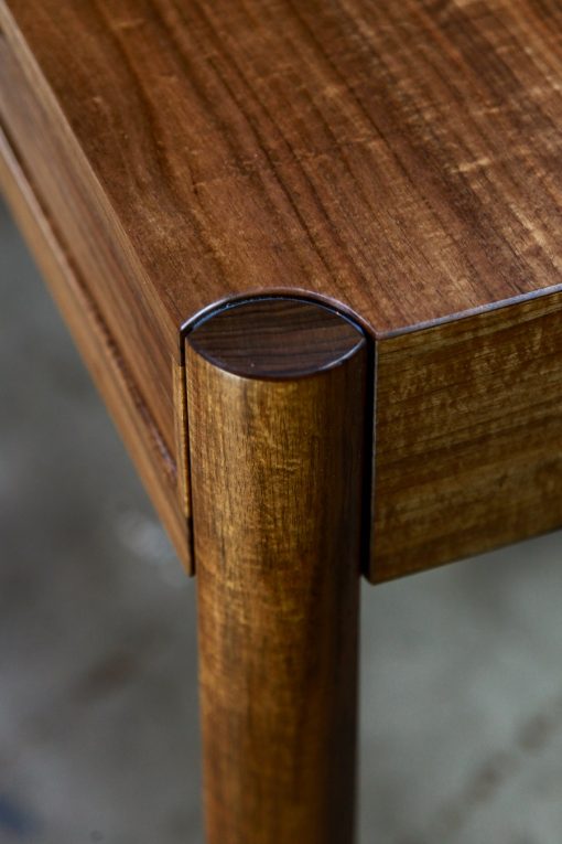 A beautifully composed hall table with figured blackwood standing in front of a timber rack in a woodworking workshop.