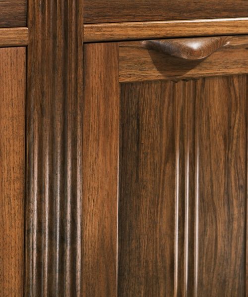 A moody photograph of a blackwood cabinet sits in front of a timber rack in a dark workshop.