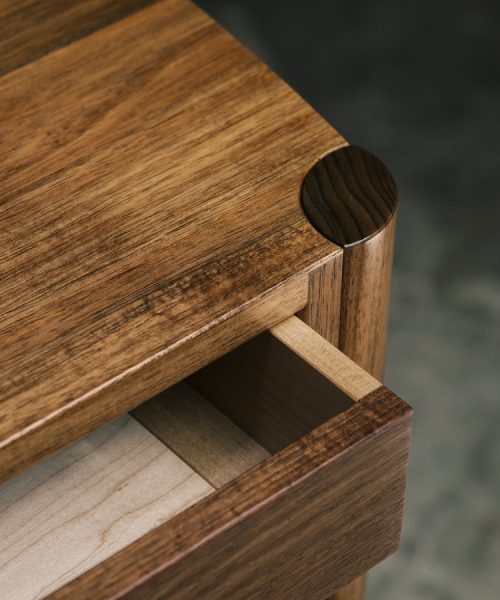 A moody photograph of a blackwood cabinet sits in front of a timber rack in a dark workshop.