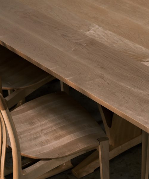 An eight-seater rectangular dining suite sitting in a woodworking workshop near a timber rack.