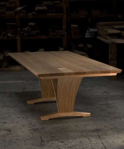 An eight-seater rectangular dining suite sitting in a woodworking workshop near a timber rack.