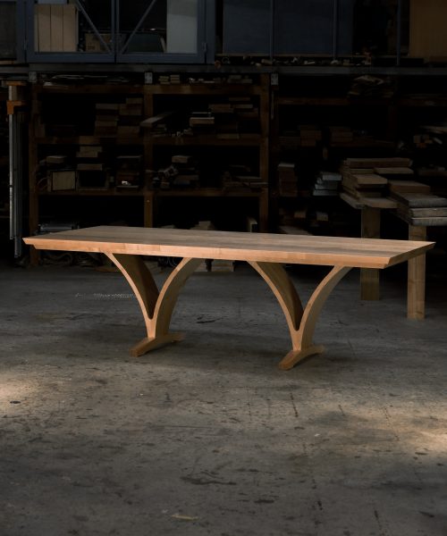 An eight-seater rectangular dining suite sitting in a woodworking workshop near a timber rack.