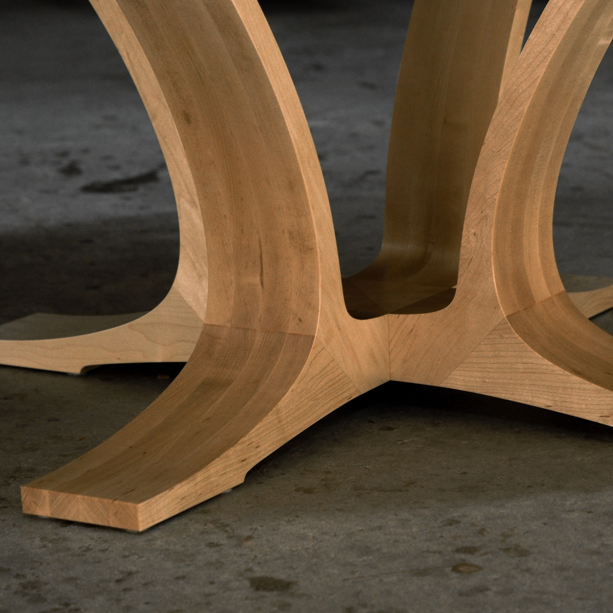An eight-seater round dining suite sitting in a woodworking workshop near a timber rack.