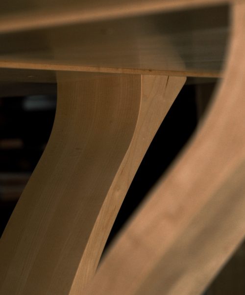 An eight-seater round dining suite sitting in a woodworking workshop near a timber rack.