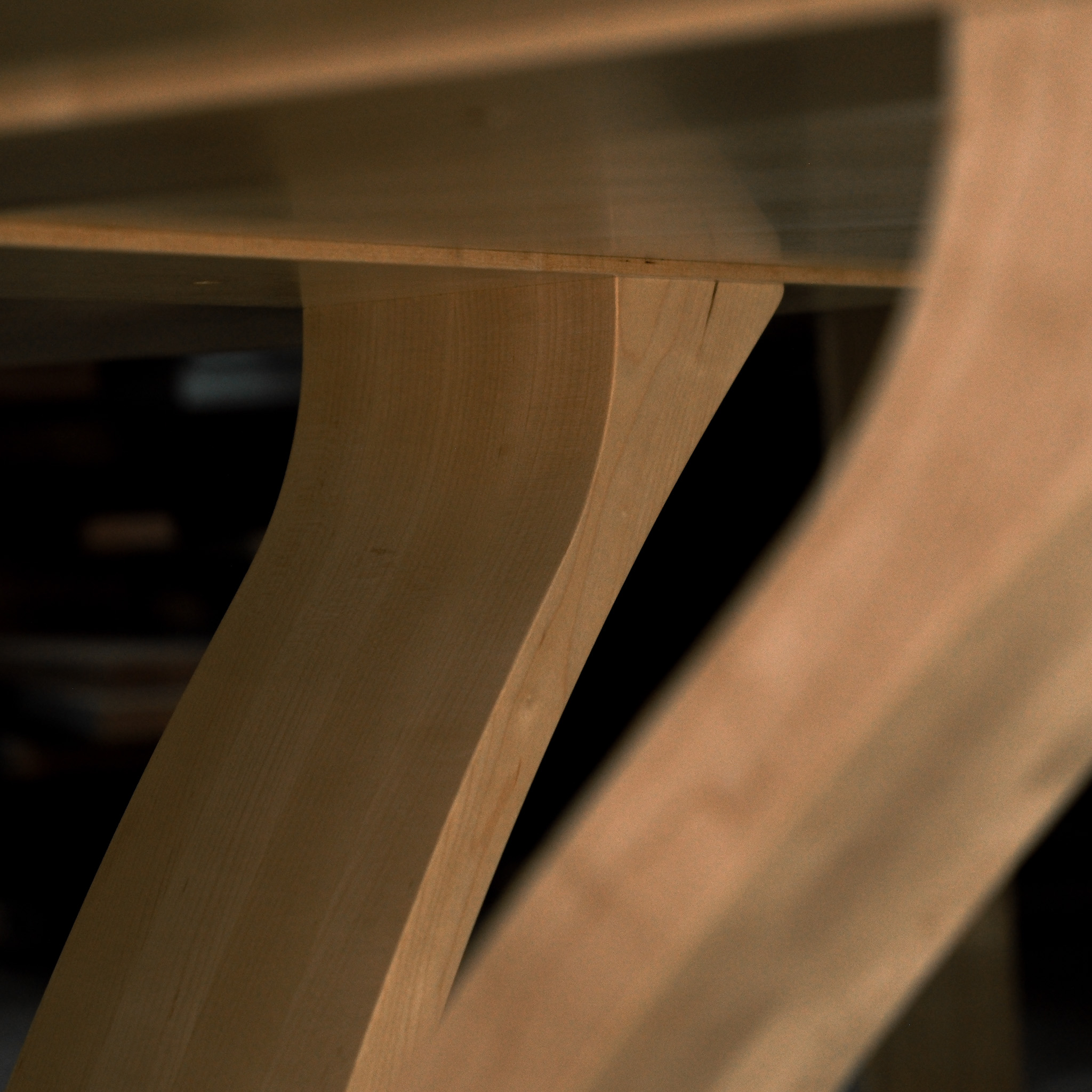 An eight-seater round dining suite sitting in a woodworking workshop near a timber rack.
