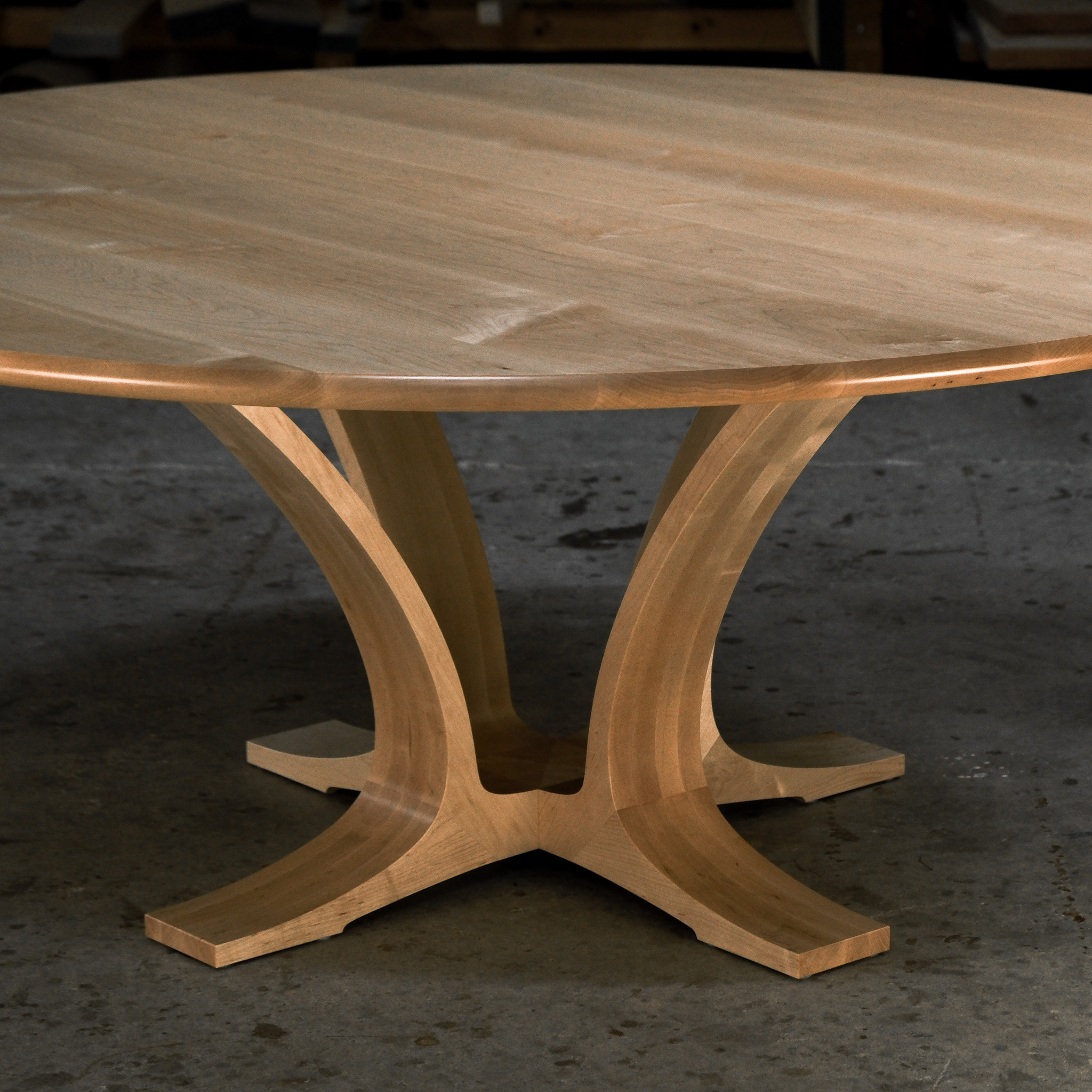 An eight-seater round dining suite sitting in a woodworking workshop near a timber rack.