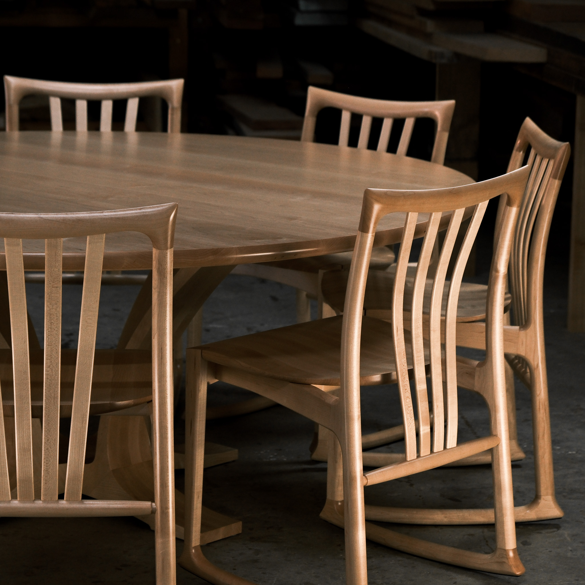 An eight-seater round dining suite sitting in a woodworking workshop near a timber rack.