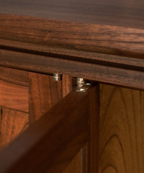 A recently finished red cedar cabinet sits in a woodworking workshop prior to delivery.