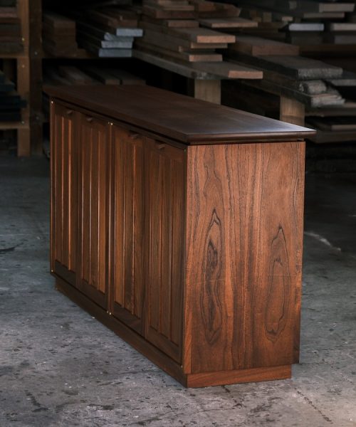 A recently finished red cedar cabinet sits in a woodworking workshop prior to delivery.