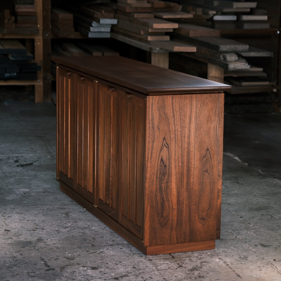 A recently finished red cedar cabinet sits in a woodworking workshop prior to delivery.