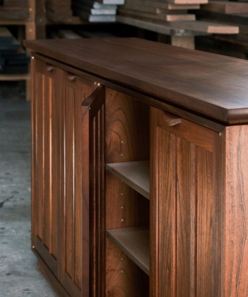 A recently finished red cedar cabinet sits in a woodworking workshop prior to delivery.