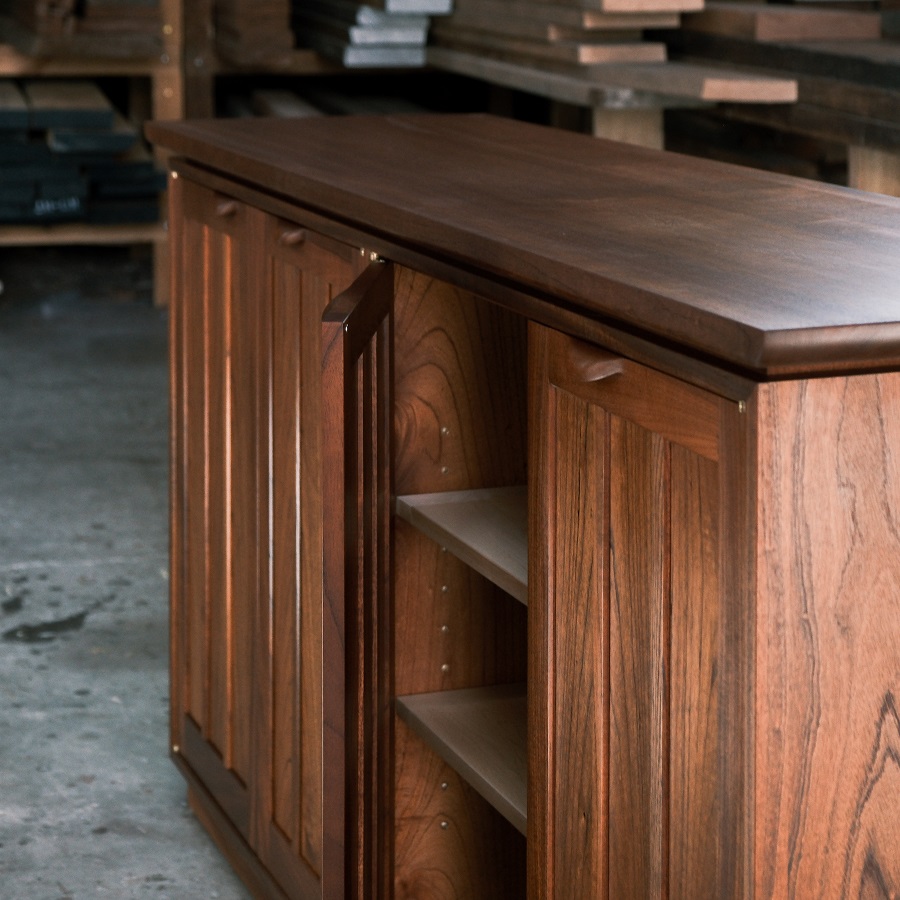 A recently finished red cedar cabinet sits in a woodworking workshop prior to delivery.