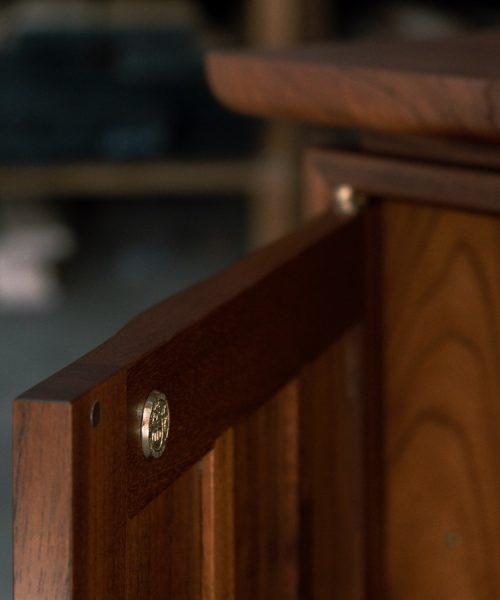 A recently finished red cedar cabinet sits in a woodworking workshop prior to delivery.