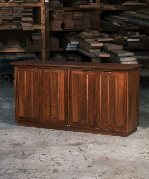 A recently finished red cedar cabinet sits in a woodworking workshop prior to delivery.