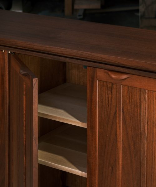 A recently finished red cedar cabinet sits in a woodworking workshop prior to delivery.