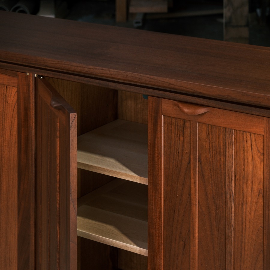 A recently finished red cedar cabinet sits in a woodworking workshop prior to delivery.